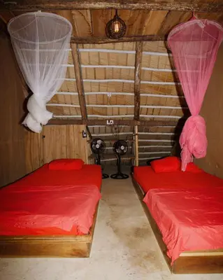 two beds in a room with red sheets and curtains at Ganesh Village Community in Colorado