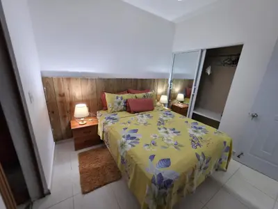 a bedroom with a bed with a yellow comforter and a mirror at Playa y arena in San Felipe de Puerto Plata