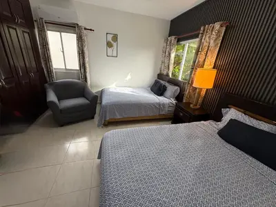 a bedroom with two beds and a chair and a lamp at Brisa de mar in San Felipe de Puerto Plata
