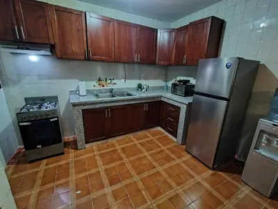 a kitchen with wooden cabinets and a stainless steel refrigerator at Comfortable and quiet double room in Santo Domingo