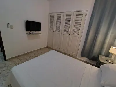 a white bedroom with a bed and a television at Comfortable and quiet double room in Santo Domingo