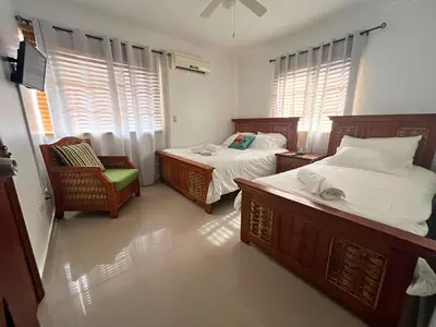 a bedroom with two beds and a chair and windows at Apartamento Rosa Hermosa in Punta Cana