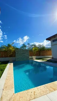 a swimming pool with blue water in a yard at Bello atardecer in Punta Cana