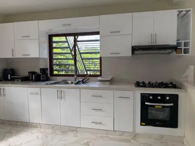 a kitchen with white cabinets and a sink and a window at Villa Rafael in Bayaguana