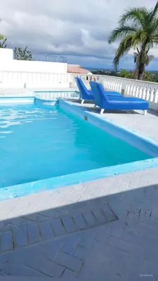 a swimming pool with two blue lounge chairs next to it at Villa Maryluz in Alto de los Castillos