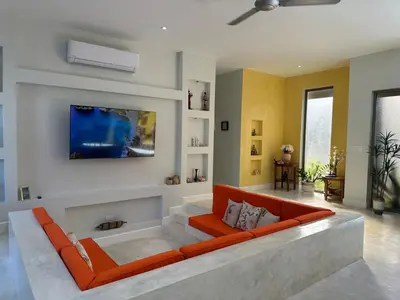a living room with an orange couch in the middle at Villa Olam - 9 pax, 4 min de la playa in Las Galeras