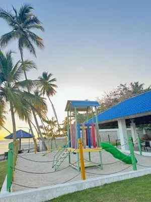 a playground with slides and palm trees on a beach at Las Olas Apartment, Juan Dolio in Guayacanes