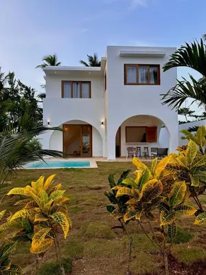 a white house with palm trees in front of it at Villa Coral Blue in Playa Bonita in Las Terrenas