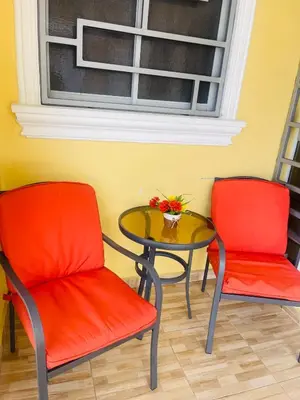 two red chairs and a glass table with a table at Apt 2 Bedrooms a Pasos del Malecon y la Playa in San Felipe de Puerto Plata