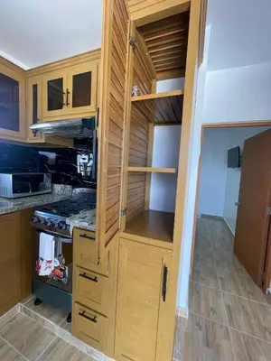 a kitchen with wooden cabinets and a stove top oven at Luxurious 1BR apartment with ocean and mountain views, central in San Felipe de Puerto Plata
