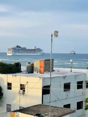 a white building with a cruise ship in the water at Luxurious 1BR apartment with ocean and mountain views, central in San Felipe de Puerto Plata