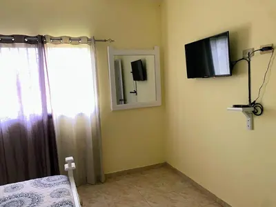 a bedroom with a bed and a mirror and a television at Tu Casa En Pedernales in Pedernales