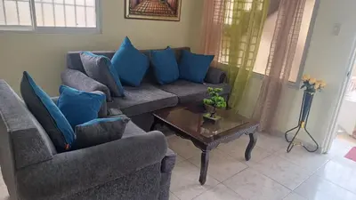 a living room with two couches and a table with blue pillows at Dona Beba Guesthouse in La Caleta