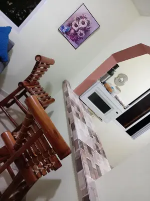 a staircase in a living room with a wooden chair at Dona Beba Guesthouse in La Caleta