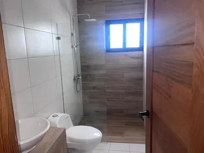 a bathroom with a toilet and a sink and a window at jardines de caleta in La Romana