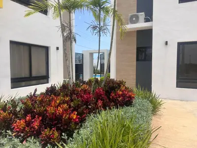 a garden with flowers and palm trees in front of a building at jardines de caleta 7 in La Romana