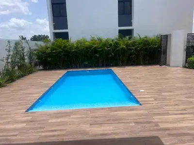 a blue swimming pool in front of a building at jardines de caleta 7 in La Romana