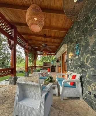 a patio with wicker chairs and a stone wall at Villa refugio de paz in Bayaguana