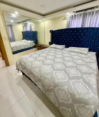 a bedroom with a bed with a blue headboard and a mirror at Charming villa in San Pedro de Macorís