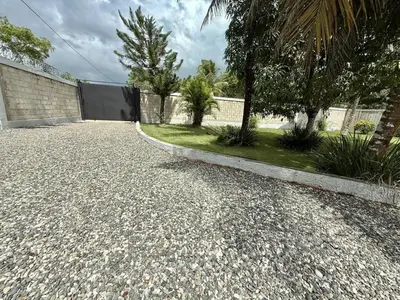 a driveway of a house with a fence and trees at Charming villa in San Pedro de Macorís