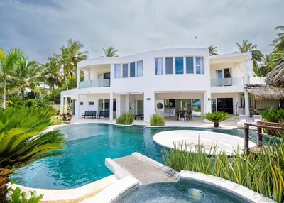 a large white house with a swimming pool in front of it at Villa Emoción Del Mar - Beachfront Luxury Villa