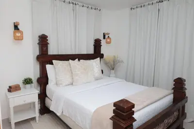 a bedroom with a large bed with white sheets at Rustic Charm, Apartment in the heart of Santiago in Santiago de los Caballeros