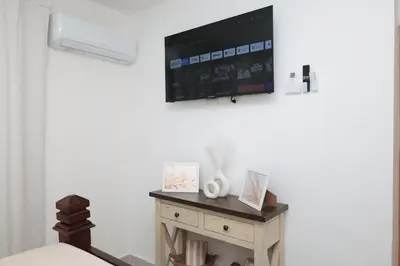 a room with a table with a tv on the wall at Rustic Charm, Apartment in the heart of Santiago in Santiago de los Caballeros