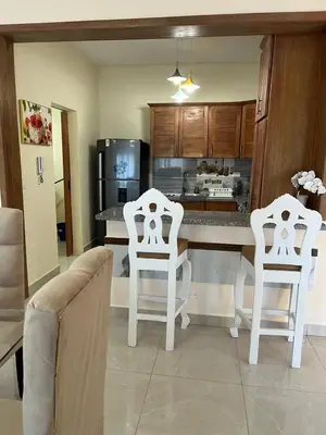 a kitchen with two white chairs and a counter at Residencial Torre del Atlantico in Puerto Plata