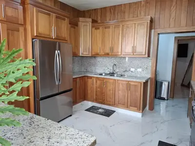 a kitchen with wooden cabinets and a stainless steel refrigerator at Villa with Pool Terrace and 3 minutes to the beach in Puerto Plata