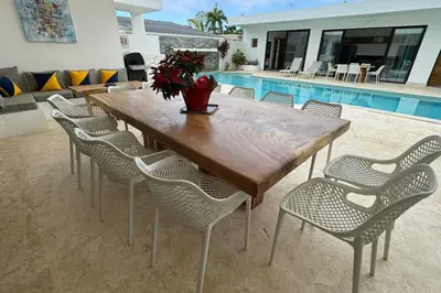 a wooden table and chairs next to a pool at 5 Bedroom Villa With BBQ and Washer in Las Terrenas
