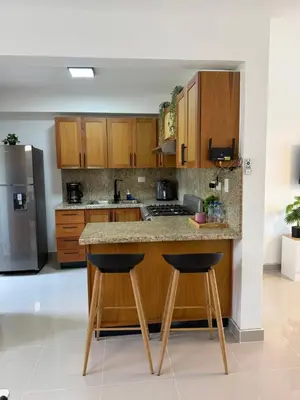 a kitchen with wooden cabinets and a island with two stools at Luxurious Apartment in Santiago de los Caballeros
