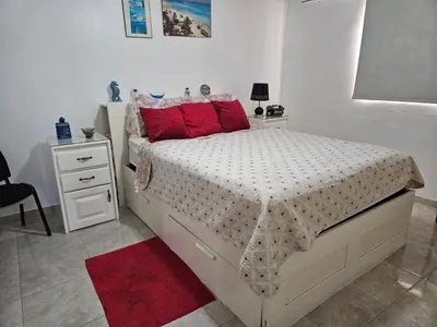 a white bedroom with a bed with red pillows at Garden II in Boca Chica