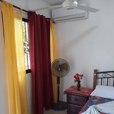 a bedroom with a bed and a fan and a window at B&B KeisyAlba Punta Rucia in Punta Rucia