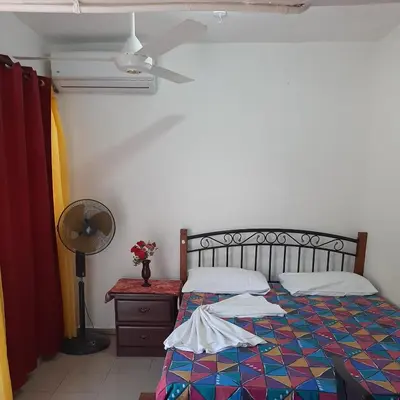 a bedroom with a bed and a fan and a table at B&B KeisyAlba Punta Rucia in Punta Rucia