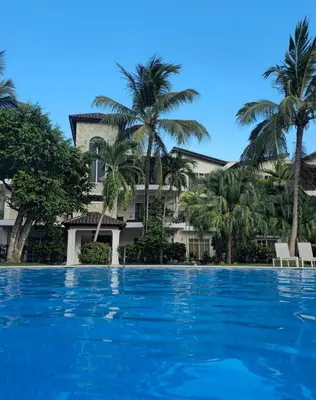 a pool in front of a building with palm trees at Residencial El Carey in Punta Cana