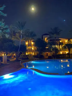 a large blue swimming pool at night with the moon at Residencial El Carey in Punta Cana
