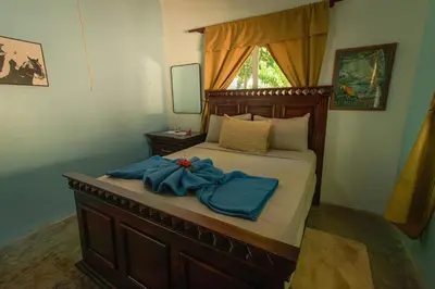 a bedroom with a bed with blue sheets and a mirror at The SeaDog Inn-Oceanfront Villa in Cabrera