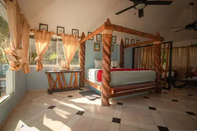 a bedroom with a bed with a wooden canopy at The SeaDog Inn-Oceanfront Villa in Cabrera