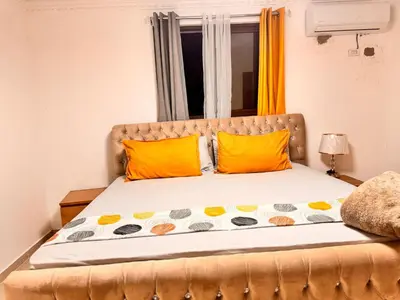 a bedroom with a bed with orange pillows and a window at Santiago Amazing 4bedrooms Apt for group, spectacular WIFI, close to all fun in Santiago de los Caballeros
