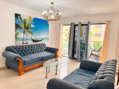 a living room with a blue couch and a chandelier at Santiago Amazing 4bedrooms Apt for group, spectacular WIFI, close to all fun in Santiago de los Caballeros