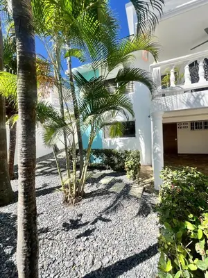 a white house with palm trees in front of it at Hermosa villa frente al mar in San Felipe de Puerto Plata