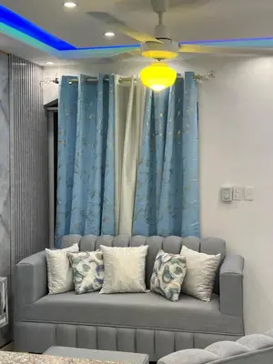 a couch in a living room with blue curtains at Lujoso apartamento cerca del aeropuerto SDQ in La Caleta