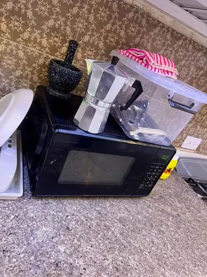 a black microwave sitting on top of a counter at Lujoso apartamento cerca del aeropuerto SDQ in La Caleta
