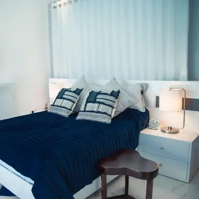a bedroom with a blue bed with pillows and a chair at Caribbean getaway Villa 30 in Puerto Plata