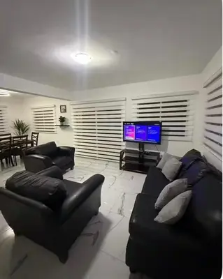 a living room with a black leather couch and a flat screen tv at Luxury Villa in Muñoz, Puerto Plata in Puerto Plata