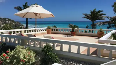 a balcony with an umbrella and chairs and the beach at Ecolodge Vistamar in Los Patos
