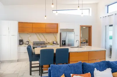 a kitchen with a table and some blue chairs at Newly Built Luxury Private 3 Bedroom Pool Villa in Sosúa