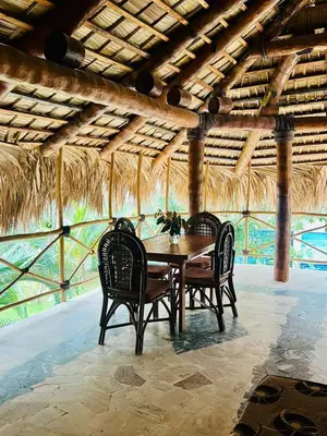 a dining room table with two chairs and a thatched ceiling at La Cabañita de Jardín del Coco in Las Galeras