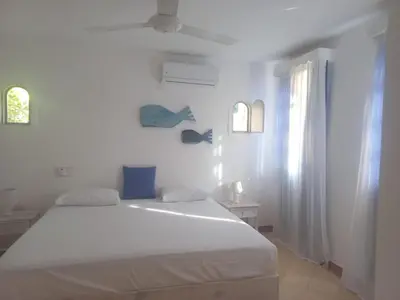 a white bedroom with a white bed and a window at Rose&mary in Las Terrenas