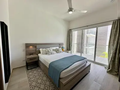 a bedroom with a bed and a large window at Corner 2BDR in Coral Bay 2 in front of Hard Rock in Punta Cana